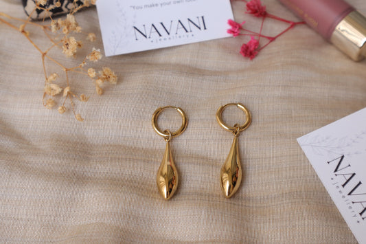 Gold drop earrings from Navani Jewellery on beige background with branding card and flowers 